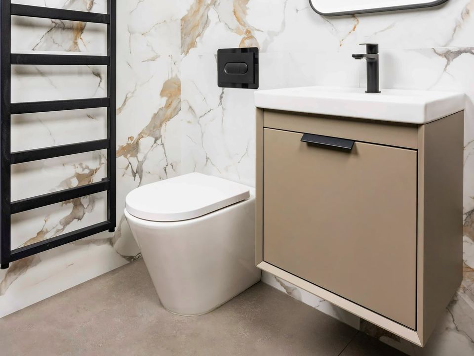 Marble-effect wall tiles behind a basin unit, toilet and black towel radiator