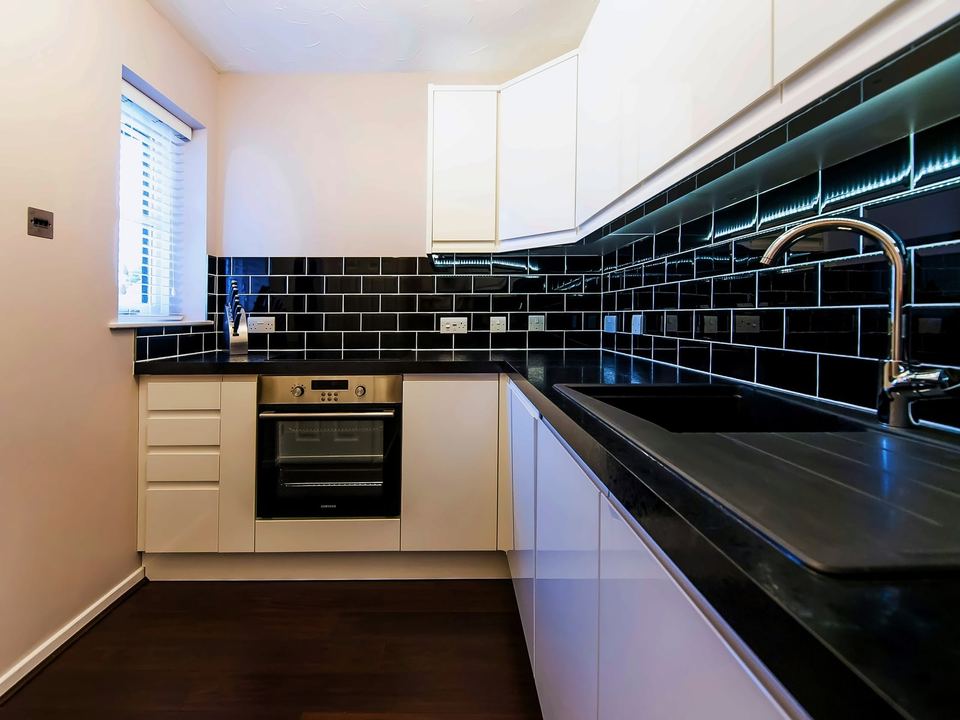 Kitchen with a black metro tile splashback under the wall units