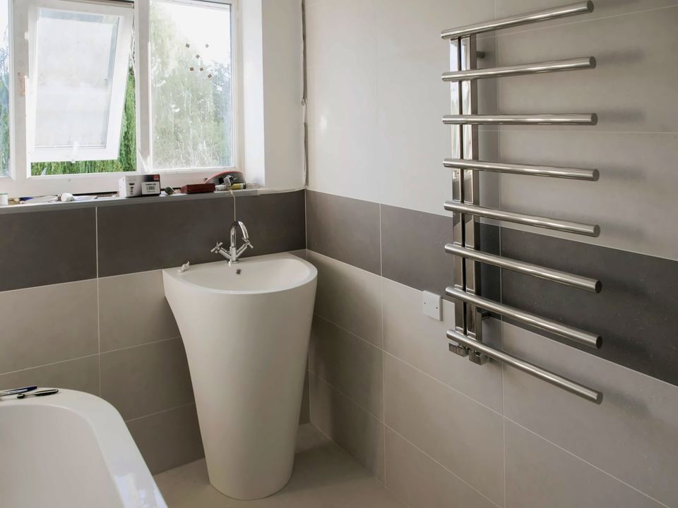 Bathroom part-way through a refit, with a chrome towel radiator and a pedestal basin