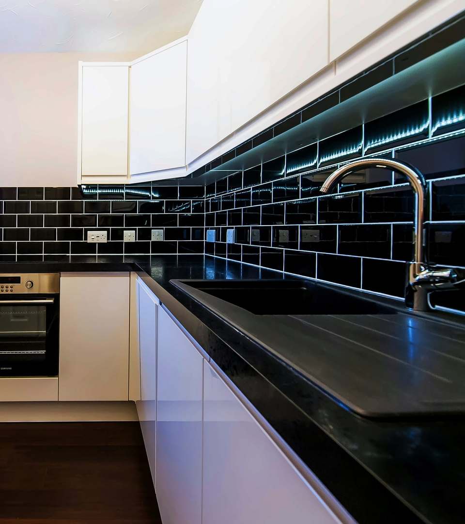 Kitchen with a black metro tile splashback under the wall units