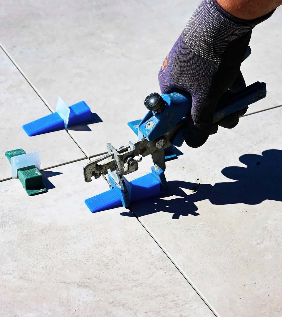 Levelling clips being tightened between large grey floor tiles