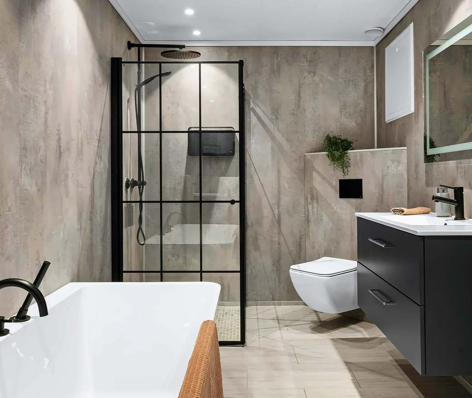 Bathroom with grey large-format wall tiles, a bath, a black-framed shower screen and a wall-hung toilet