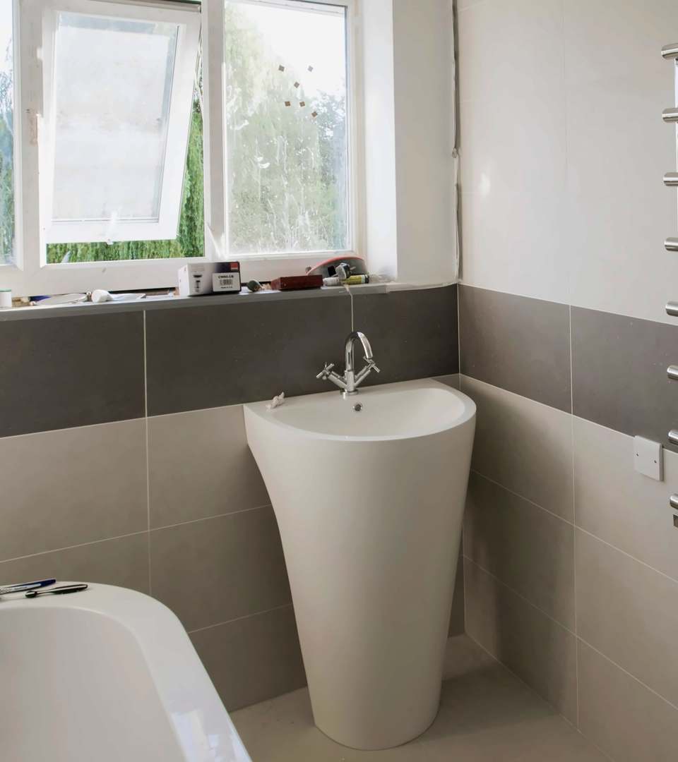 Bathroom part-way through a refit, with a chrome towel radiator and a pedestal basin